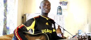 Mukalele Rogers trying out a guitar at home in Jinja Town