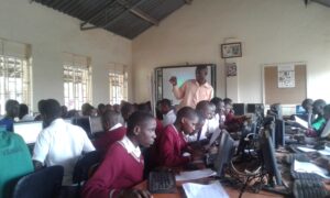 Mr. Mukalele Rogers, a Teacher at Kololo Senior Secondary School, Kampala, guiding Students using computers in a computer Lab. Digital Education is on the rise in Uganda